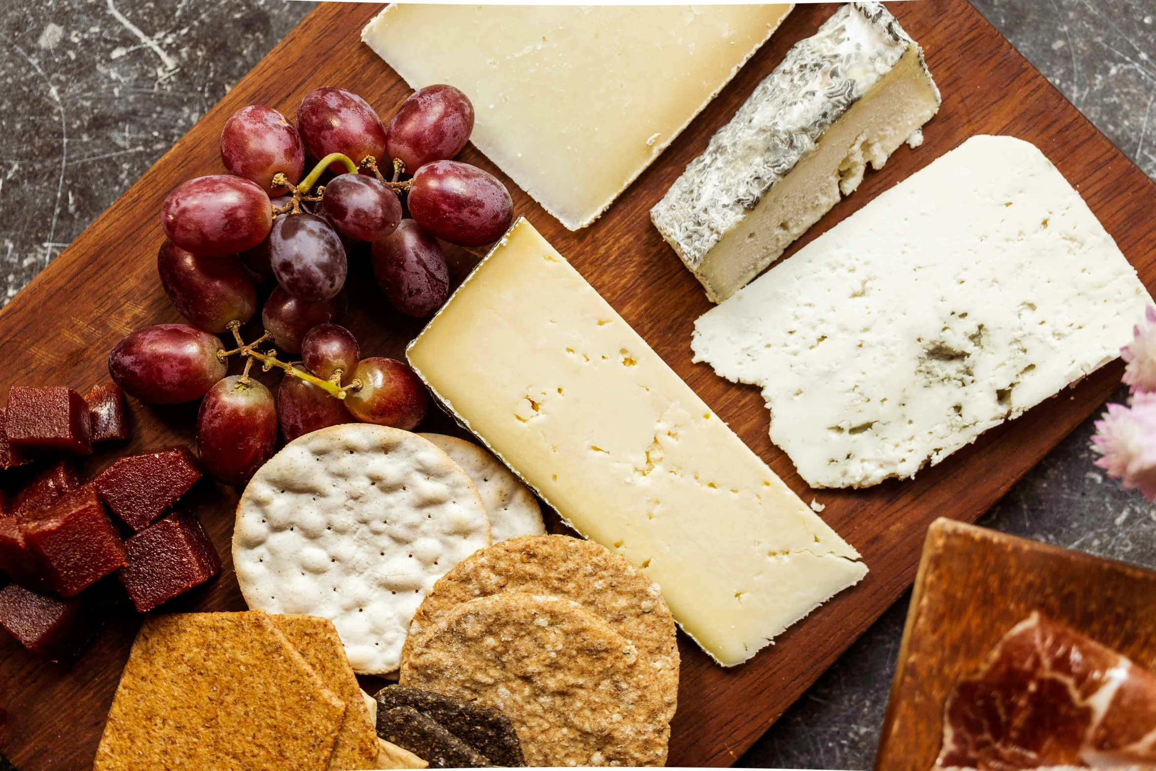 various types of cheese are laid out on a wooden board