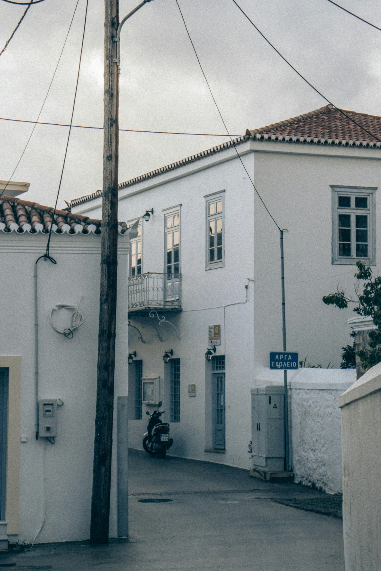 a street with a white building and a fence with some wires