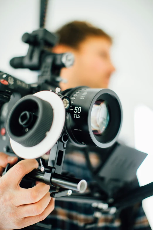 a man looking through a tripod of a camera