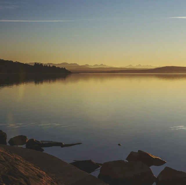 a person stands near the water with rocks