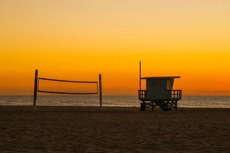 the volleyball goal is by the beach in front of the sun