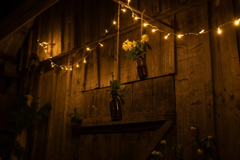 a rustic barn wall with flowers and a hanging mason jar of flowers