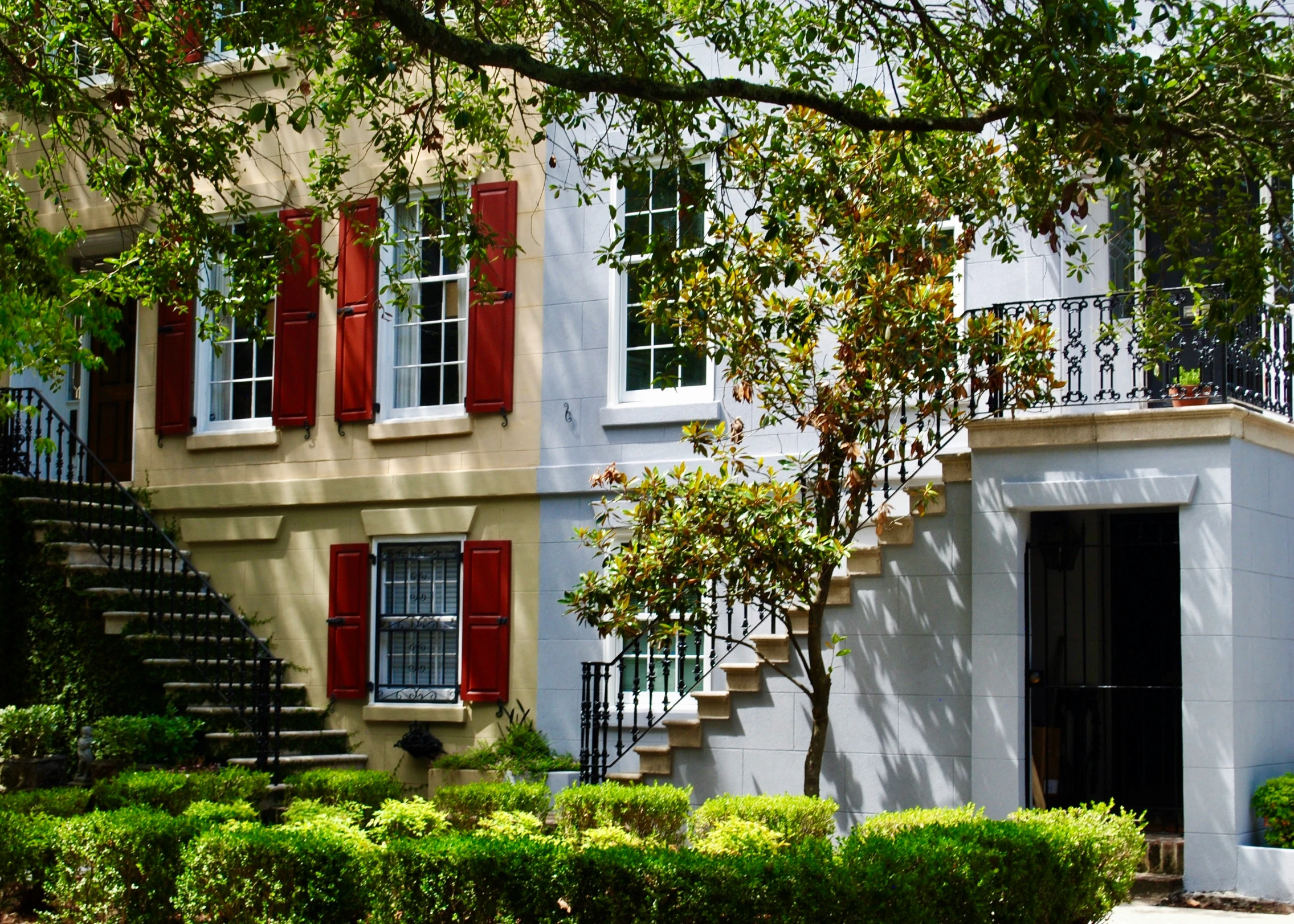 a building with a clock, trees and bushes near the sidewalk