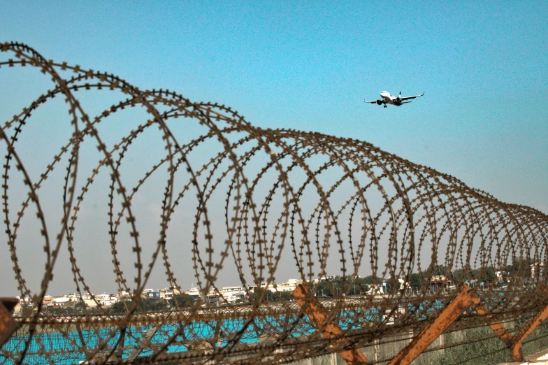 barbed wire surrounds an airplane flying above the airport