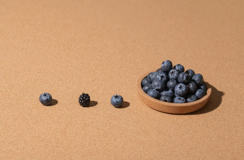 some berries in a bowl, and another berry on the other side