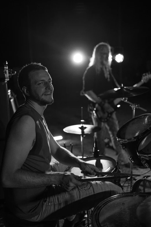 two people that are sitting down in front of drums