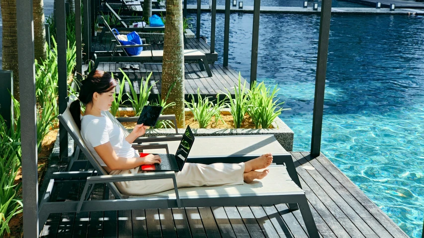 woman relaxing by the water, holding a camera and recording a movie