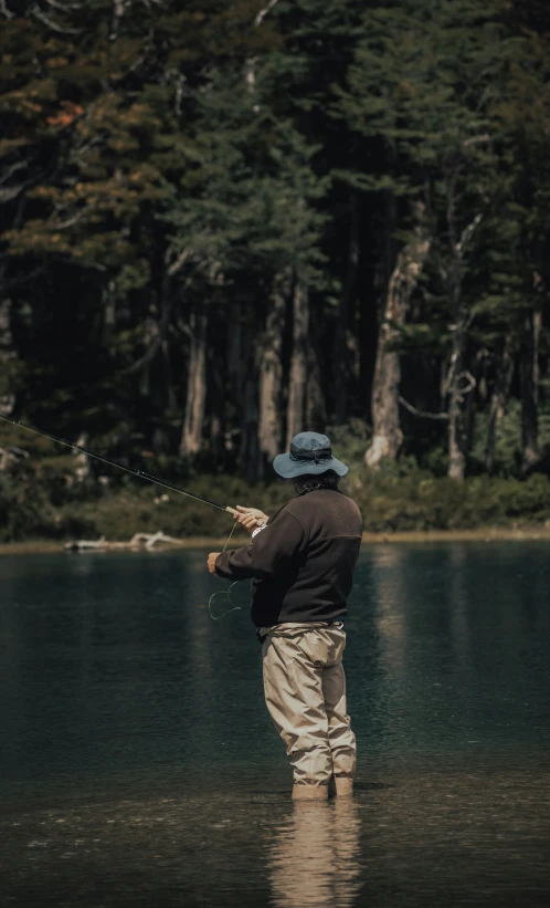 there is a man standing in the water, holding a fishing pole and a fishing line