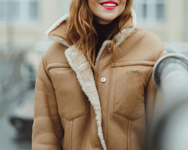 a woman in a brown jacket smiling and posing