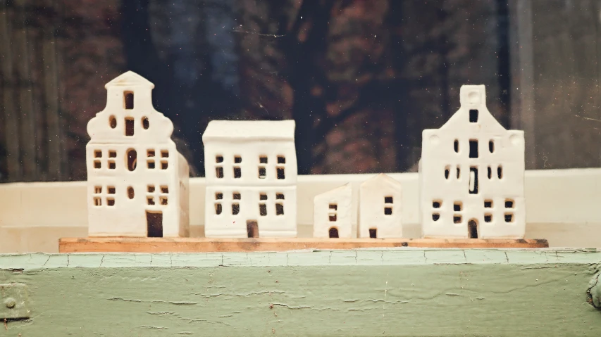 a couple of little white houses sitting on top of a window sill