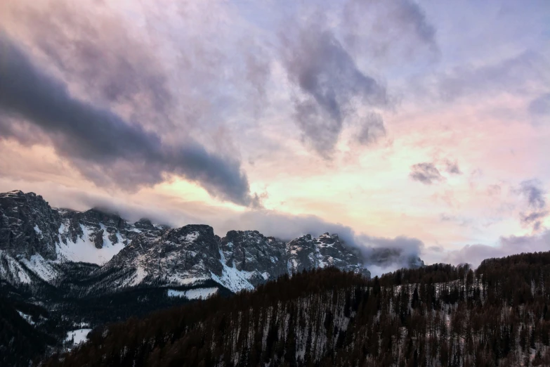 there is a mountain and some trees under a cloudy sky