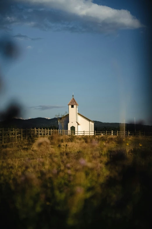 a small church in an open field surrounded by tall grass