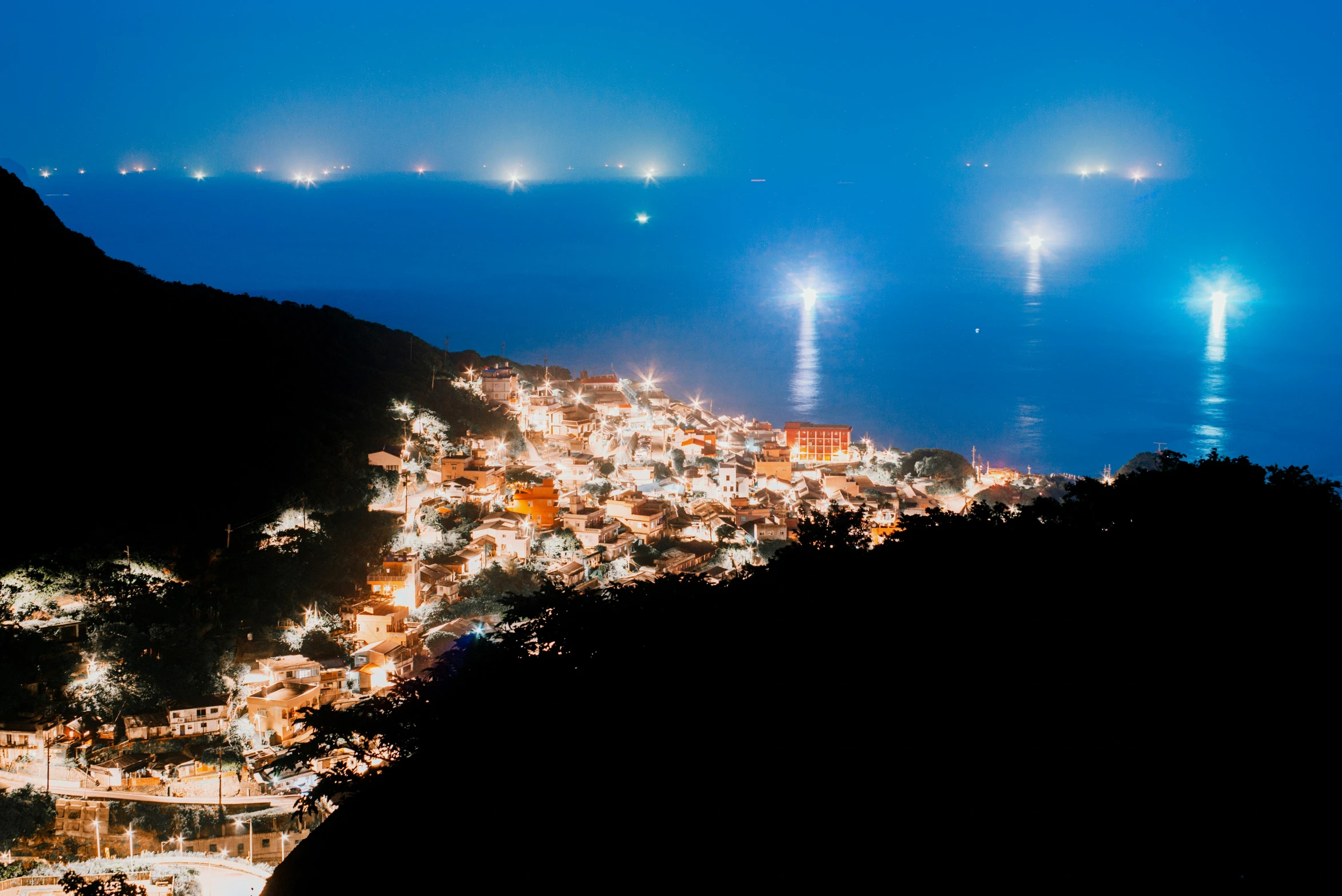 a night view of mountains and a city at night