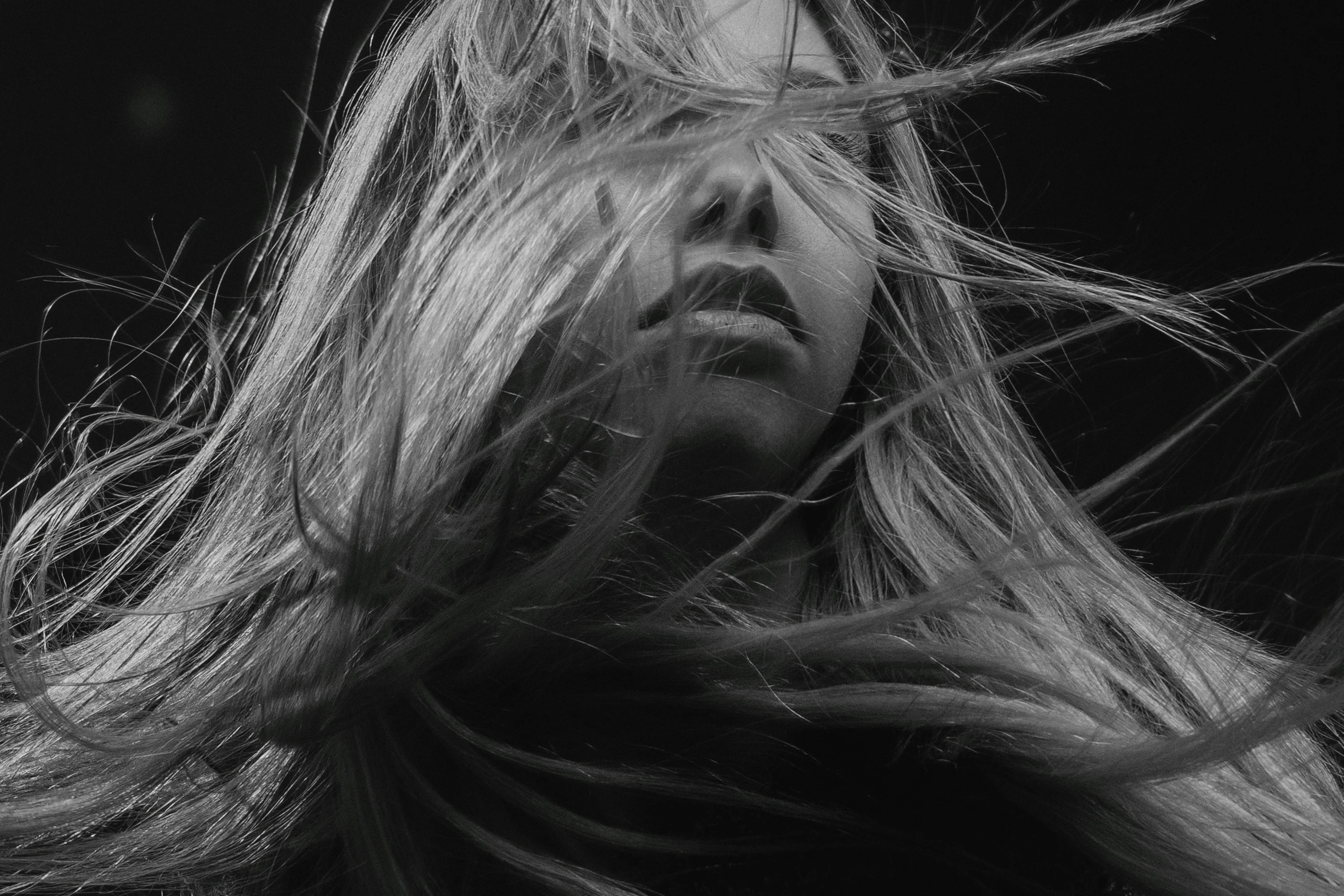 black and white po of a woman's hair blowing in the wind