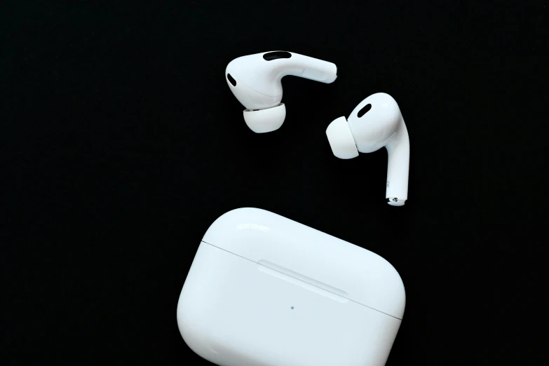 a pair of earphones with an additional case on a black surface