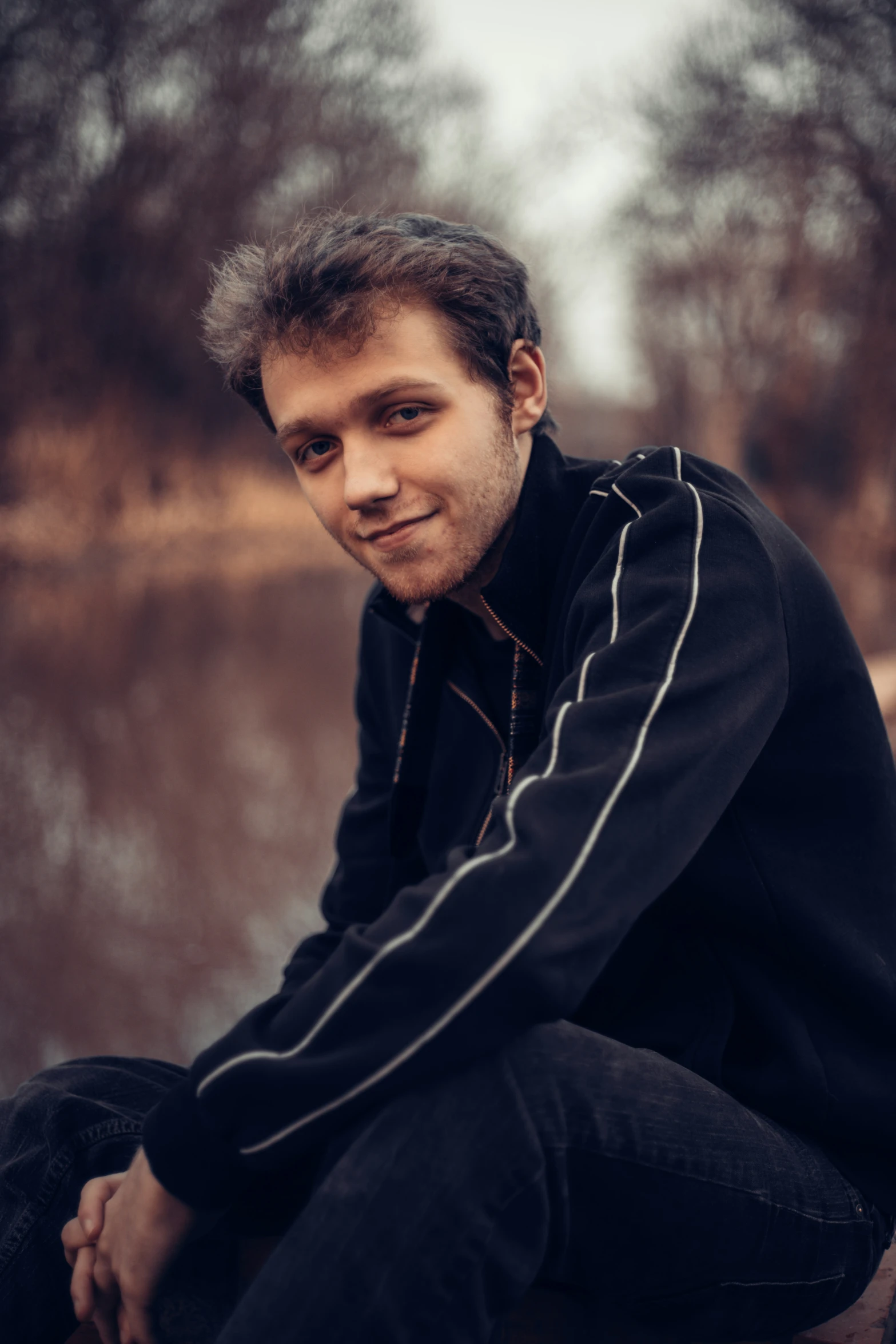 a young man is sitting near water