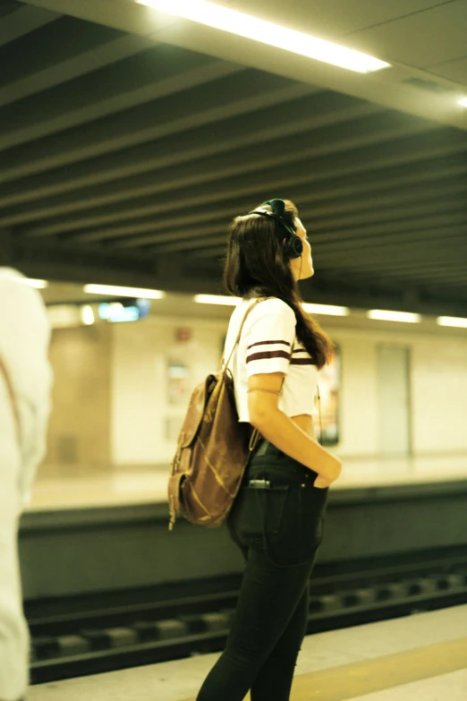 a woman with a back pack stands at a subway station