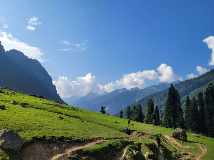 people walk along the grassy hills and valleys