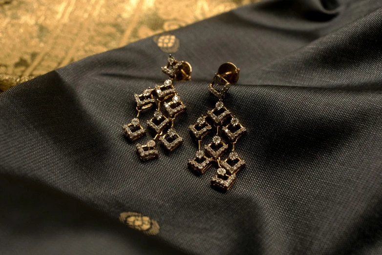 gold - plated earrings sitting on a black piece of fabric