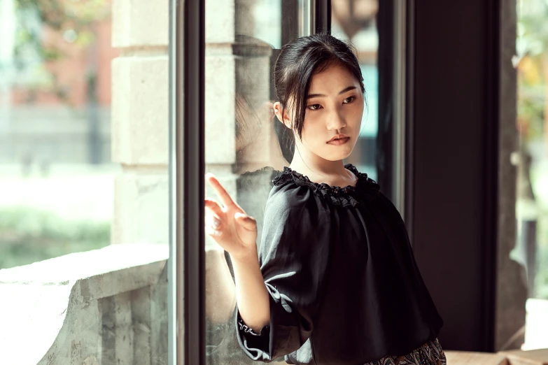 woman posing next to large glass windows looking out