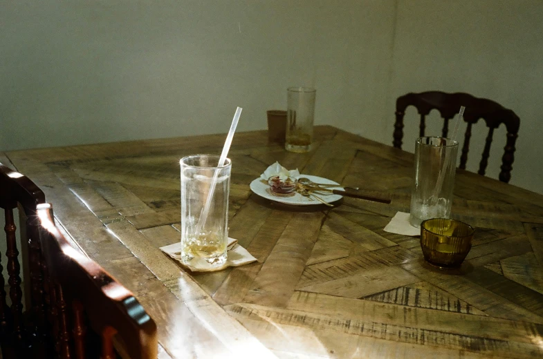 a wooden table topped with a cup and three empty glasses