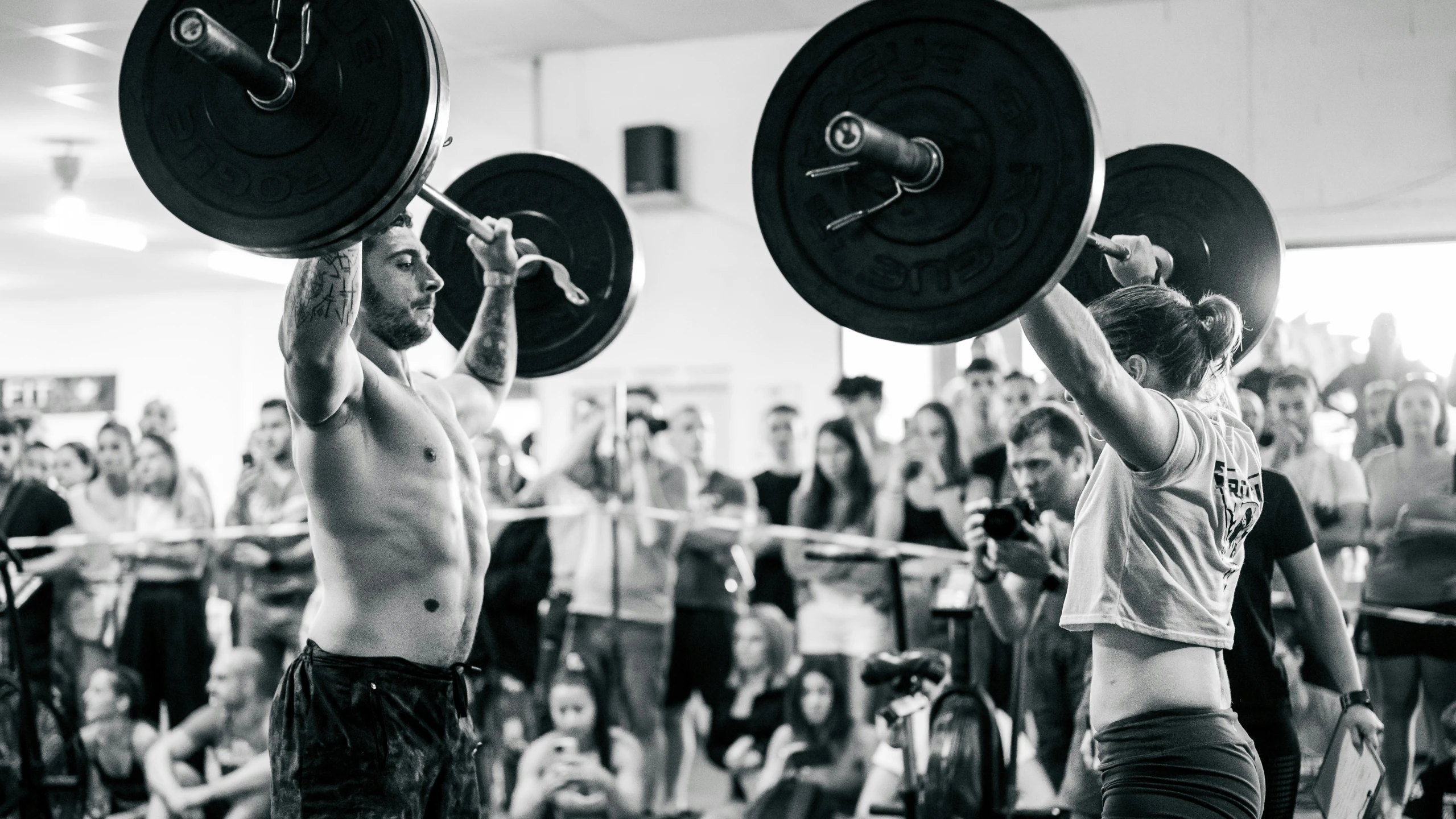 two people lifting heavy barbells while a crowd watches