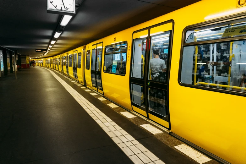 the inside of a subway that is yellow with a clock on it