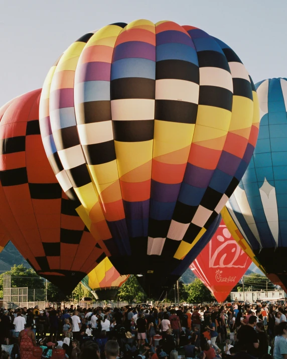 large  air balloons in different colors flying over a crowd