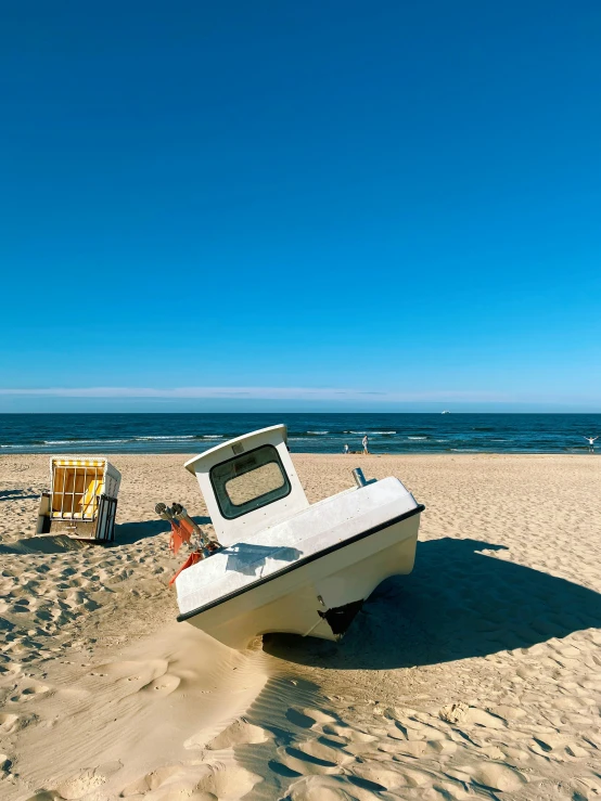 a white boat sitting in the sand on a beach