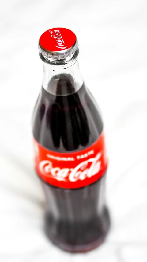 a close up of a coca - cola bottle on a white surface