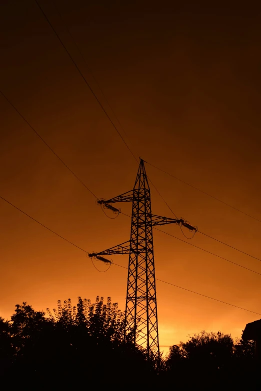 an electric power line at sunset with trees