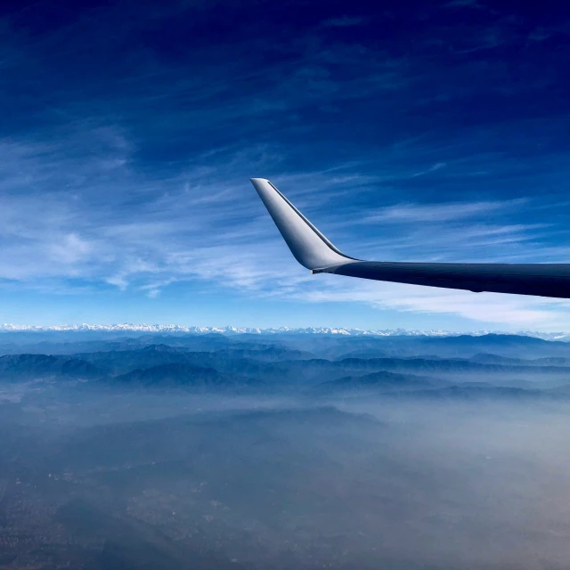 a view of the wing of an airplane flying over mountains