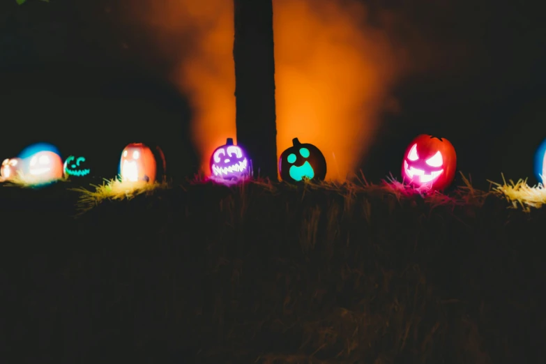 five glowing pumpkins sitting on a patch of grass