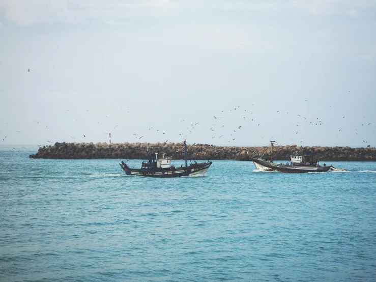 two boats floating in a bay surrounded by sand and rock