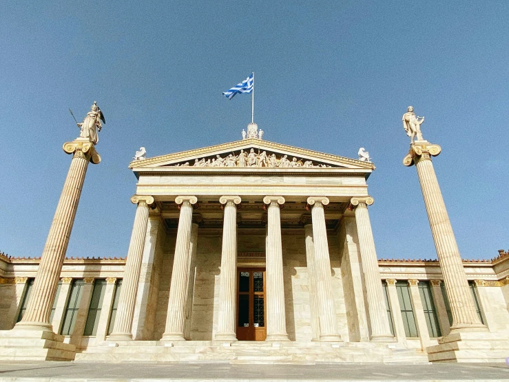 a large stone building with two pillars and a flag