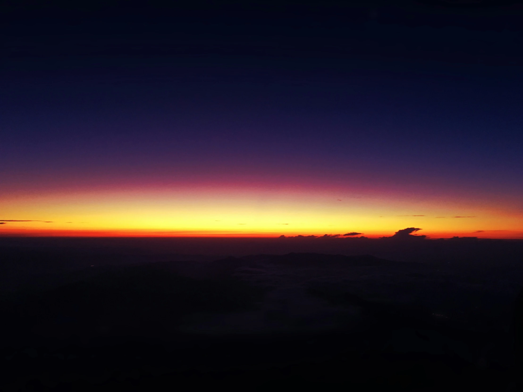 an orange and purple sun setting on the horizon over a plain