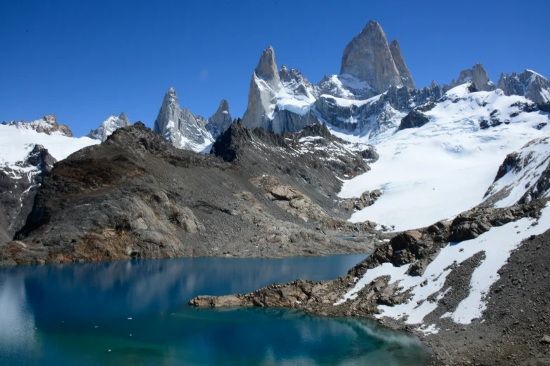 an alpine mountain landscape with a lake and mountains covered in snow