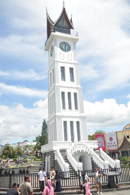 several people are walking towards a large white clock tower
