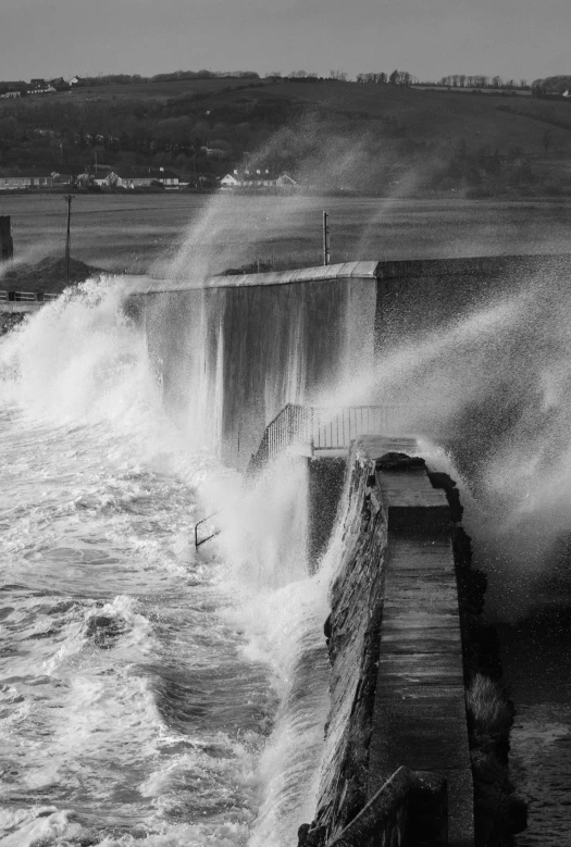 a black and white po shows waves crashing onto the sea wall