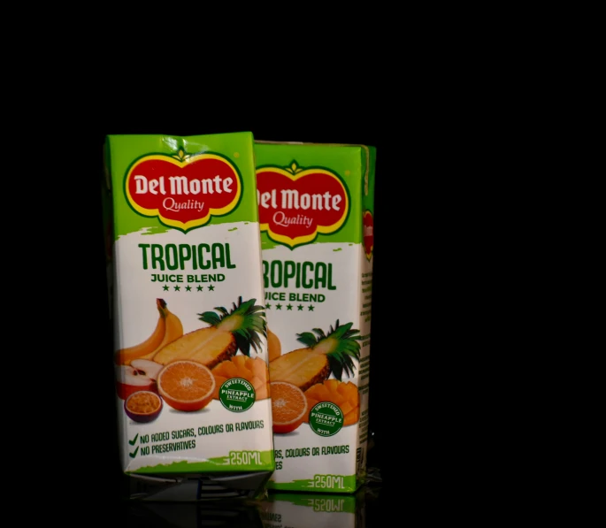 two cartons of tropical fruit juice with one orange on the side