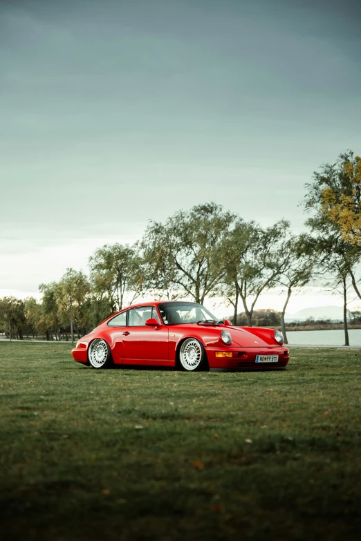 a red vintage porsche parked by a tree