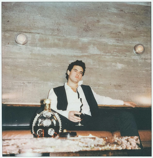 a man sitting in front of a table with a bottle of liquor