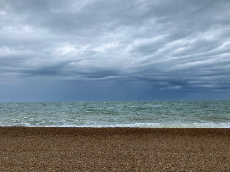 a person is holding an umbrella on the beach while the waves come ashore