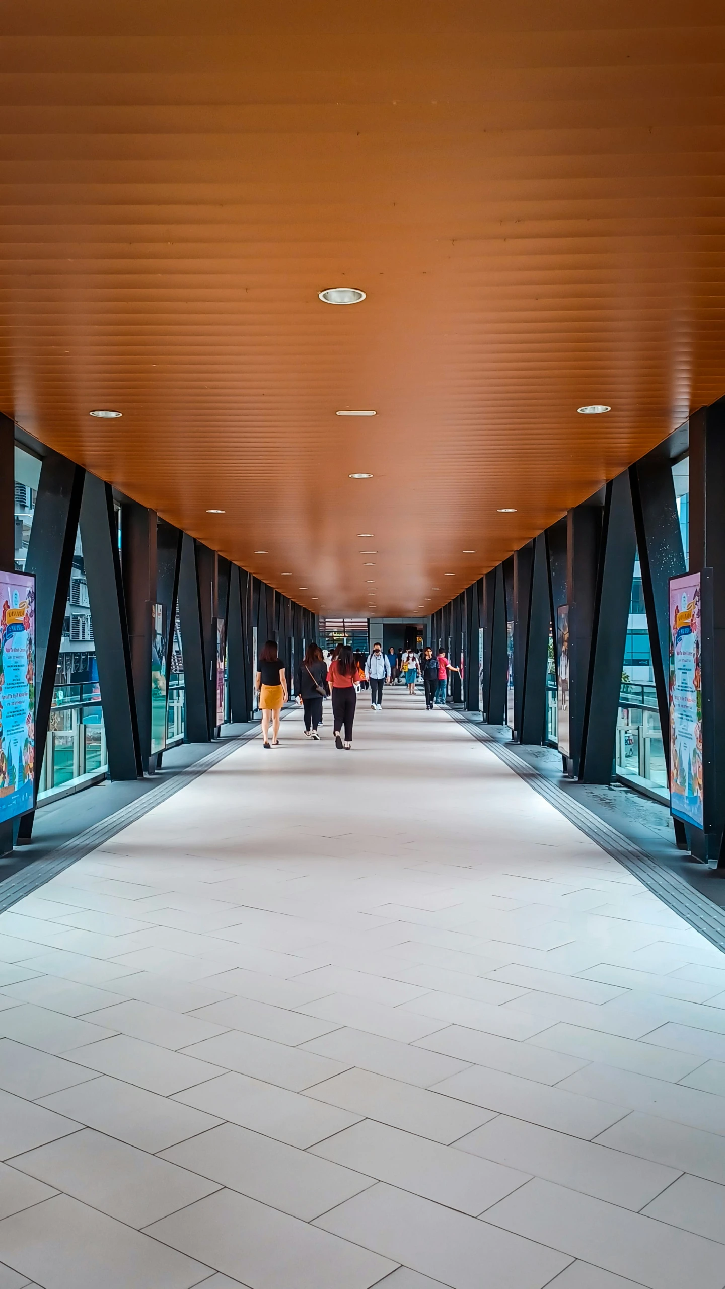 several people walking on a walkway with a tiled floor