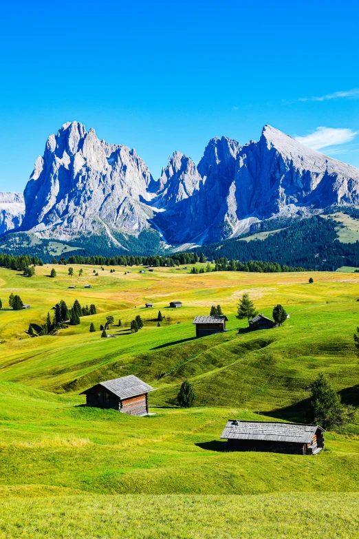 mountain ranges are behind a field with an old barn in the foreground