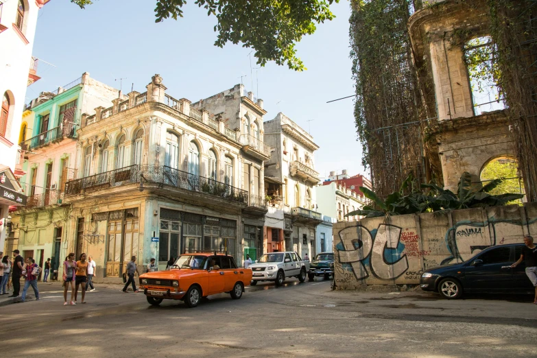 an orange car driving down a street next to tall buildings