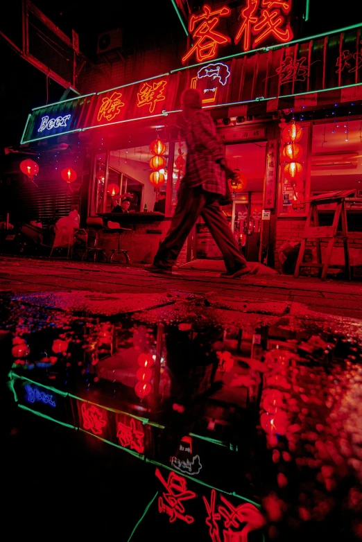 a man walking down the sidewalk in front of a neon restaurant