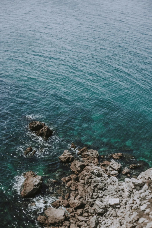 a view from the cliff looking down on rocks and water