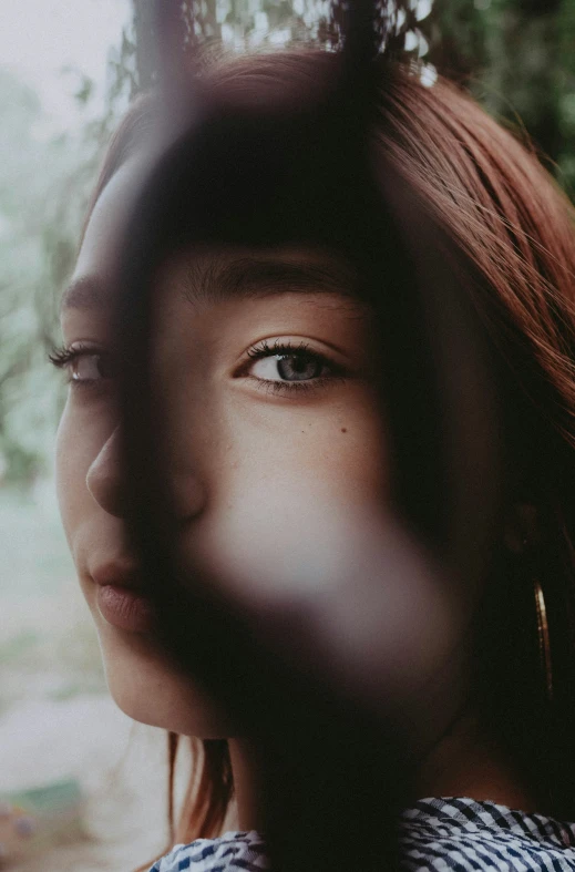 a young woman standing outside looking through the bars of her head