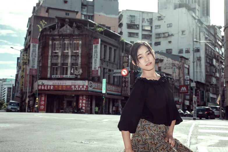 the woman stands at an intersection in front of a large building